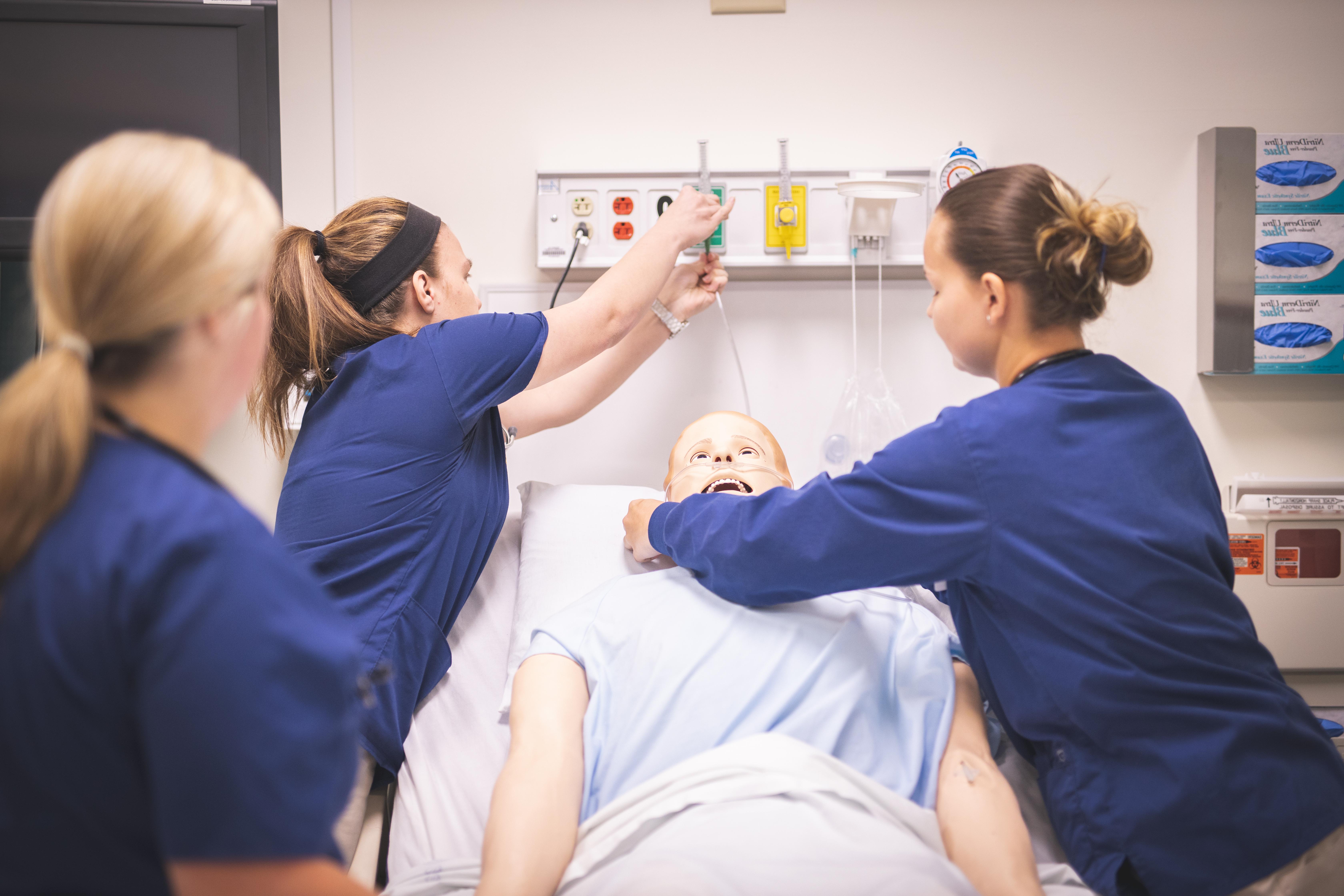 Nursing students practicing on a training dummy