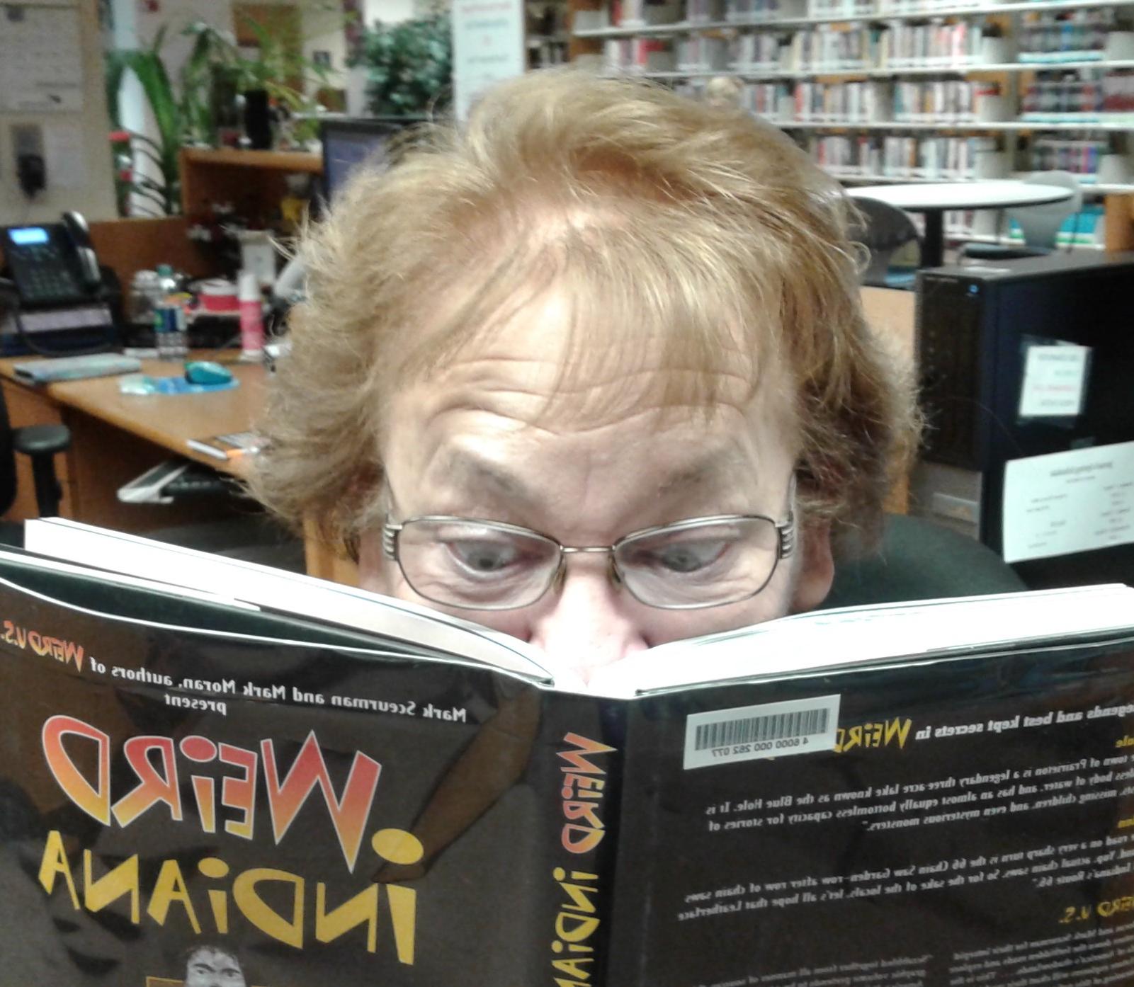 A librarian looking through the Weird Indiana book