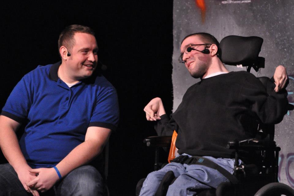Young man in a wheel chair on stage with an instructor