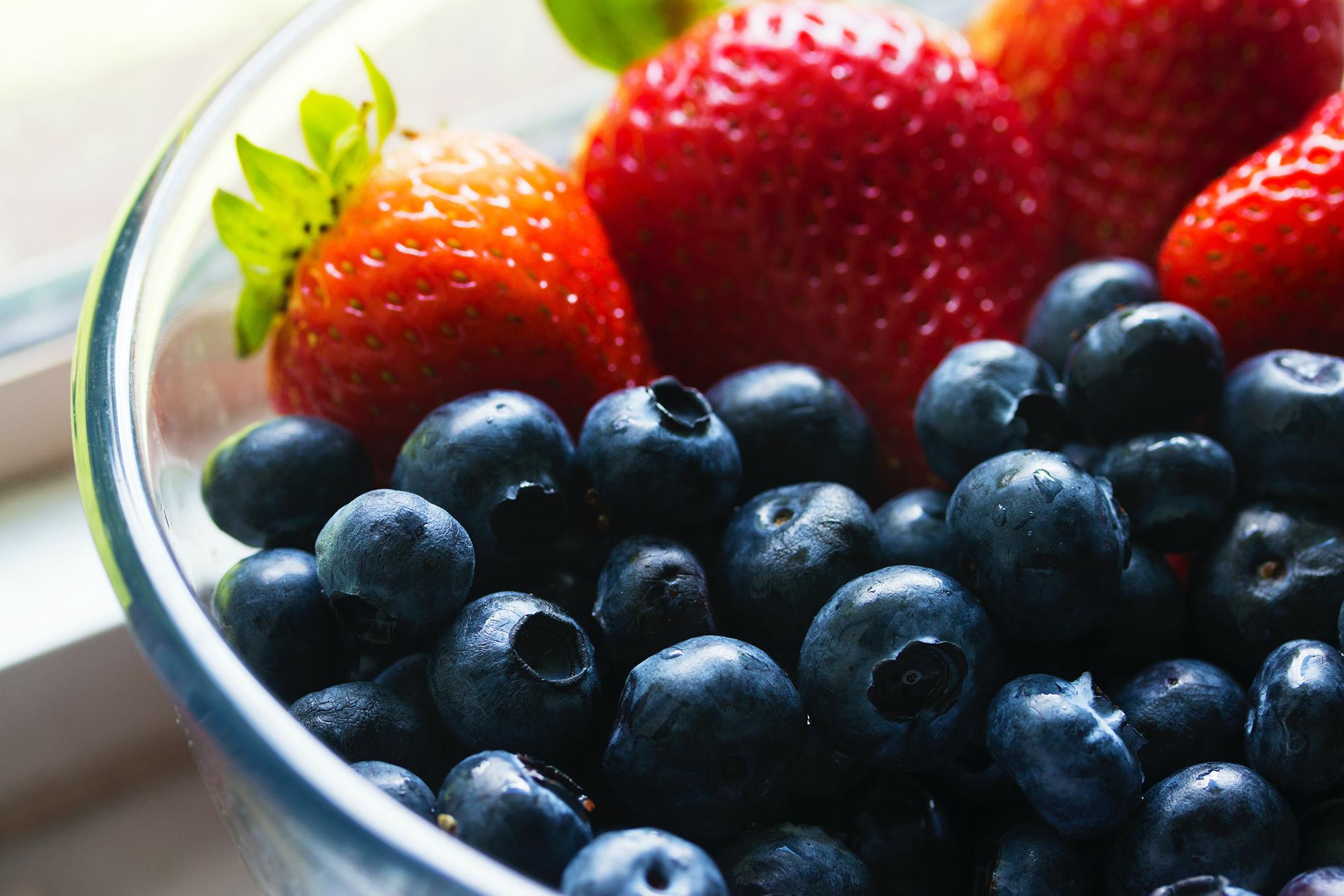 A bowl of fruit containing strawberries and blueberries