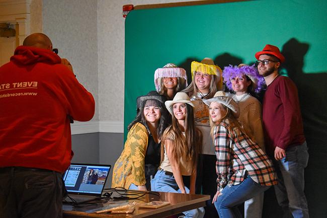 A group of students wearing cowboys hats while posing for a photo